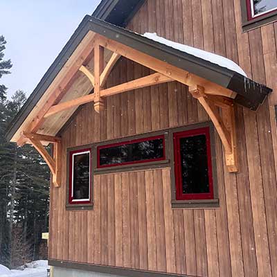 Custom timber frame home featuring decorative/structural timber trusses & brackets constructed in Vermont